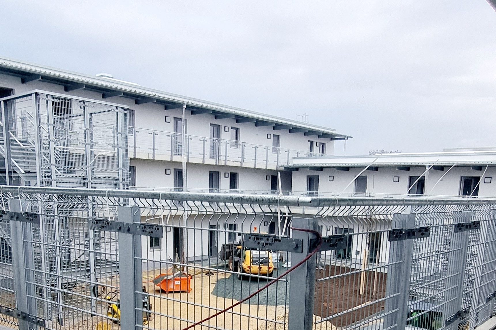 Obdachlosenunterkunft Fürth Neues, modernes Gebäude mit Baustellenequipment und geschlossenen Gitterzäunen.