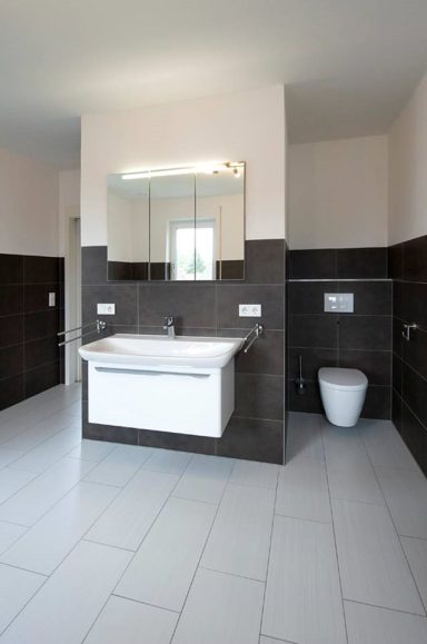 Modernes Badezimmer mit hellen Fliesen, Waschbecken und Toilette.