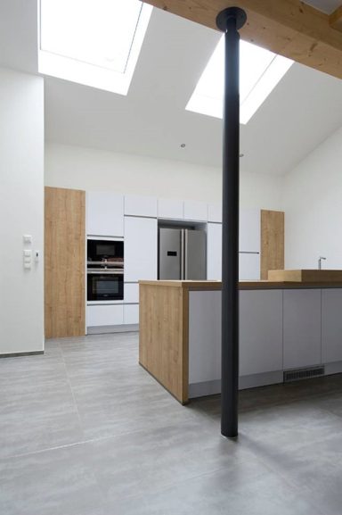 Moderne Küche mit Holz- und Metallakzenten, große Fenster und offene Raumgestaltung.