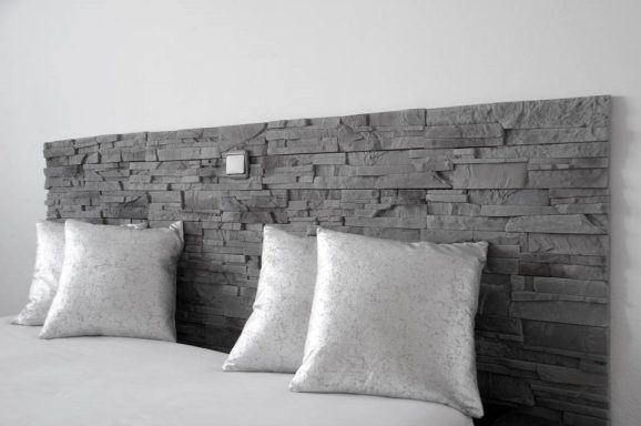 Holzkopfteil mit vier dekorativen Kissen in neutralen Farben.