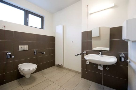 barrierefreies Kunden-WC in Bamberg, moderne, helle Toilette mit WC, Waschbecken und großem Spiegel.