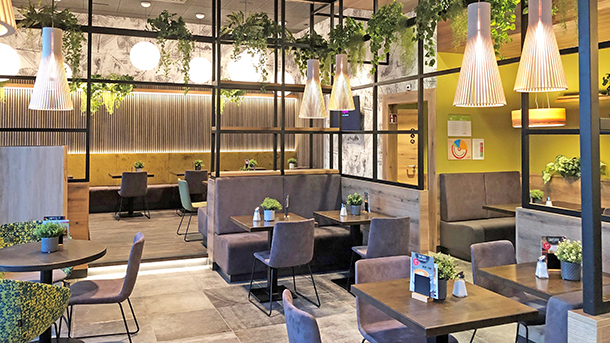 Modernes Restaurant mit gemütlichen Sitzbereichen, Pflanzen und warmem Licht.