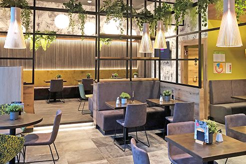 "Der Beck" in Hallstadt Modernes Cafe mit gemütlichen Sitzbereichen, Pflanzen und stylischer Beleuchtung.
