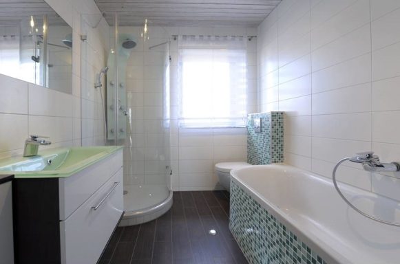 Modernes Badezimmer mit Dusche, Badewanne und hellen Fliesen.