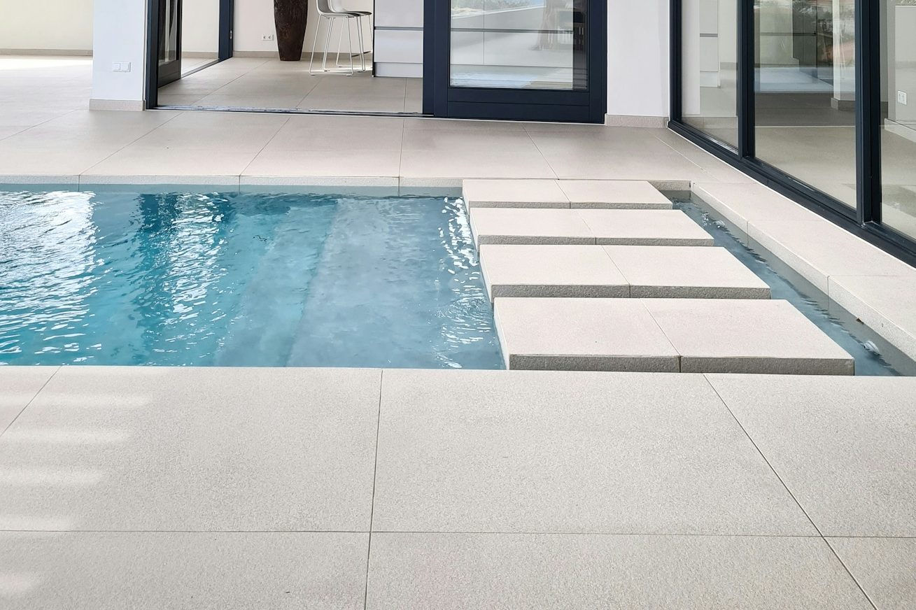 Pool Umrandung Eine moderne Terrasse mit einem Pool und Steinplatten am Rand.