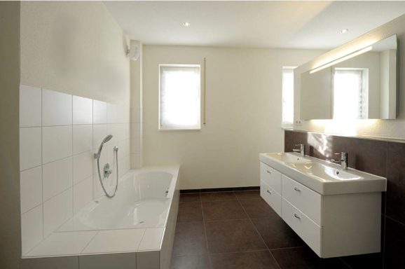 Modernes Badezimmer mit Wanne, Doppelwaschbecken und großen Fenstern.